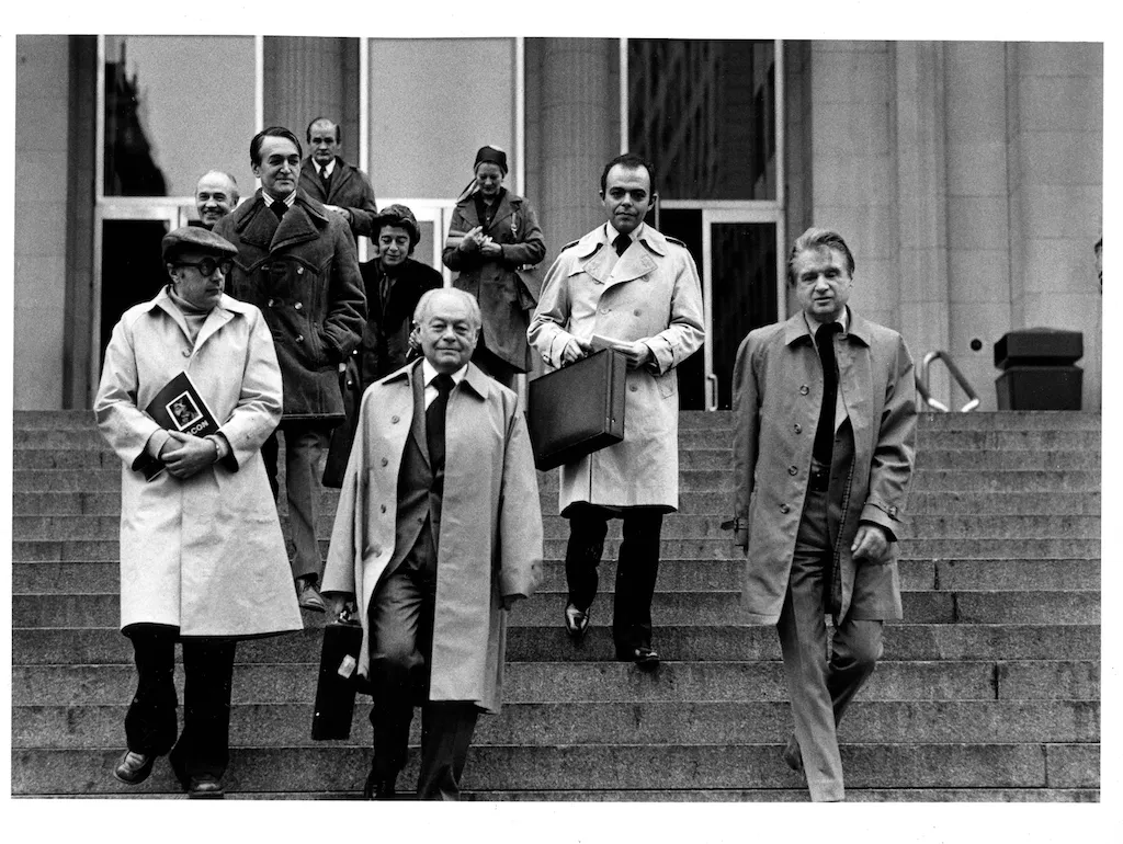 A black and white photo of a group of people walking down steps.