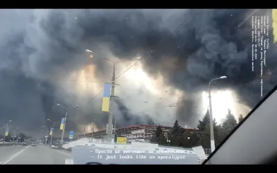 Found footage of grey smoke rising up from bombings in Ukraine, as seen through a car. 