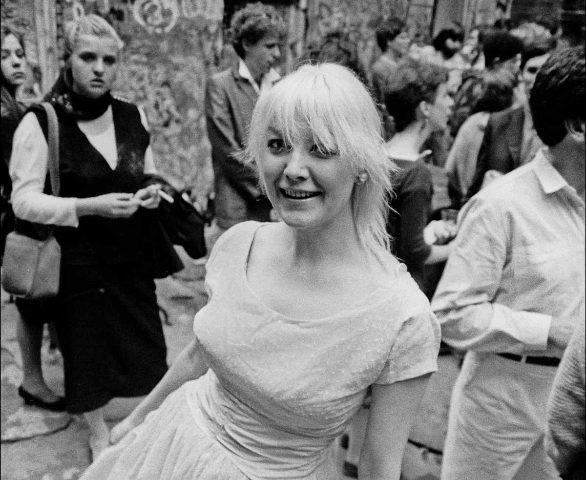 A white woman with a shag smiling amid a crowd of people.