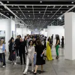 A group of people walking through the aisle of an art fair.