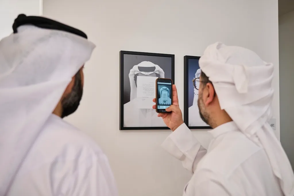 Two men in ghutras look at a picture of a man in a ghutra.