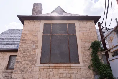 View of a rusted window on the exterior of a church.