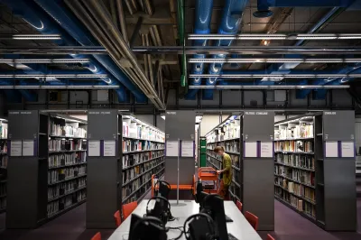 A woman at a shelf of books in a library.