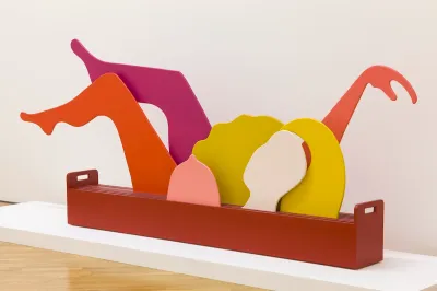 A sculpture of a woman whose breast, arms, and legs are each rendered in solid, bright colors.