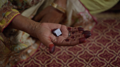 An inked hand holding out a tile.