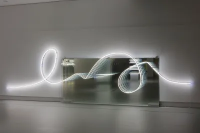 A squiggle-shaped neon lighting tube above a mirror.