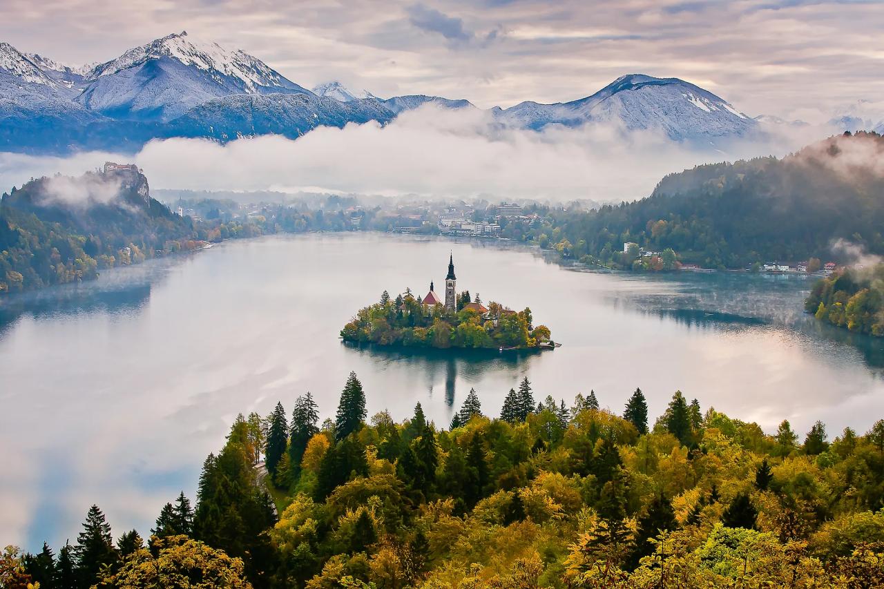 An island on a lake with mountains in the background.