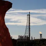 Gas flares (R-at back) at the Woodside operated North West Shelf Venture with rock (L-foreground) are shown on the Burrup Peninsula in the north of Western Australia on June 17, 2008. Piles of red rock which typify the Burrup area are the site for perhaps one million pieces of Aboriginal rock engravings several thousands of years old and considered by some to be the greatest concentration of such ancient art in the world. The peninsula in the resource-rich Pilbara region is also home to increasing amounts of industrial activity, including a gas processing plant, a fertiliser plant and iron ore facilities which are threatening the rock images of long-extinct animals and what are believed to be mythological creatures.  AFP PHOTO / Greg WOOD (Photo credit should read GREG WOOD/AFP via Getty Images)
