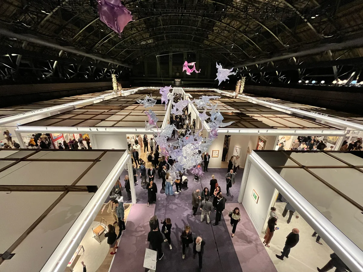 View of a vaulted drill hall with an art fair below.