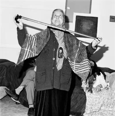 A woman in a headscarf balancing a cane between her two hands.