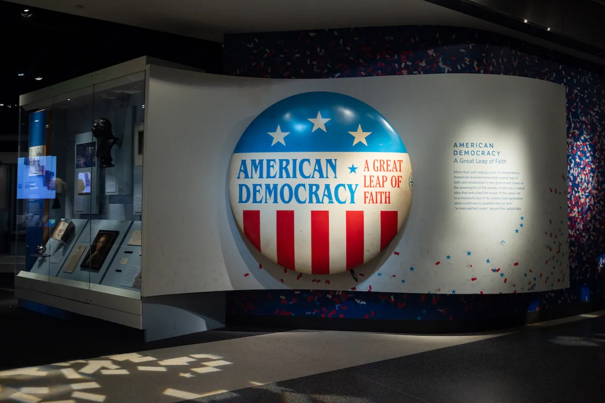 A museum display with a large button reading 