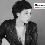 A black and white photo of a woman in a leather jacket and short hair.
