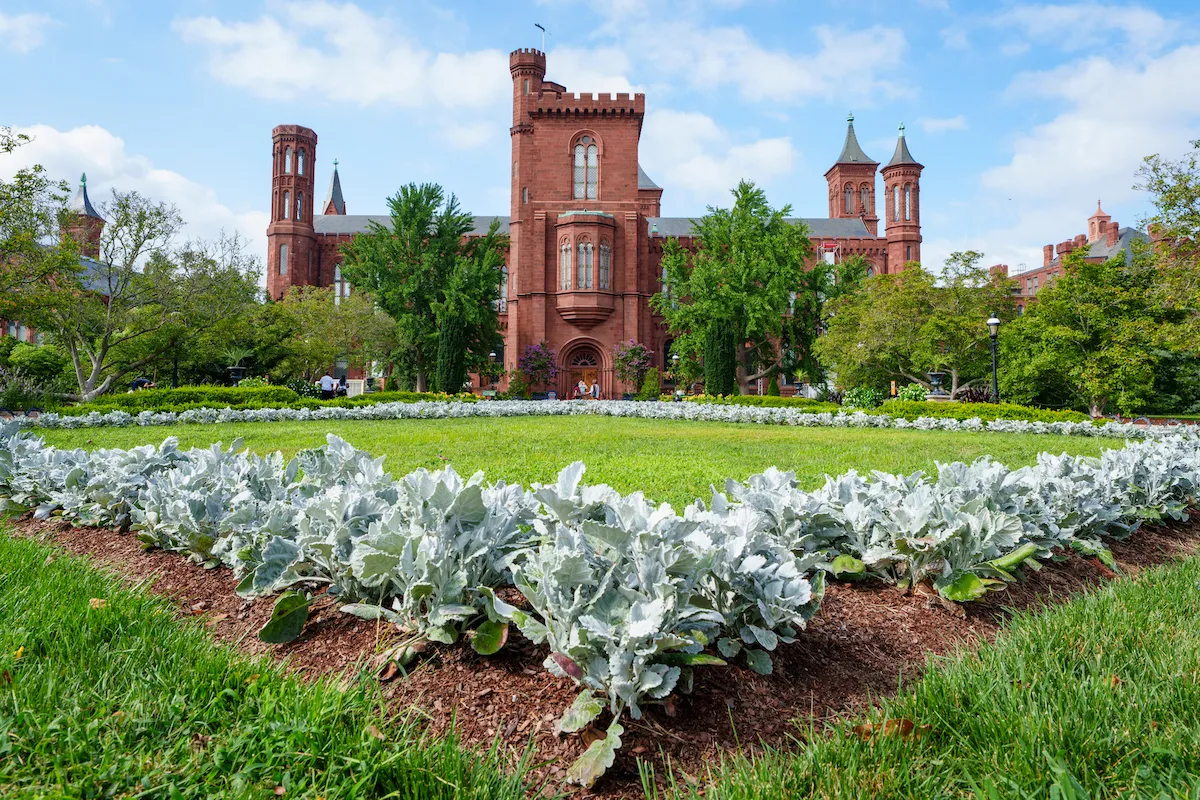 A brick castle-like structure in front of a grassy garden.