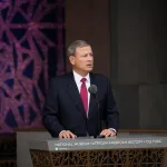 A man in a suit at a podium.