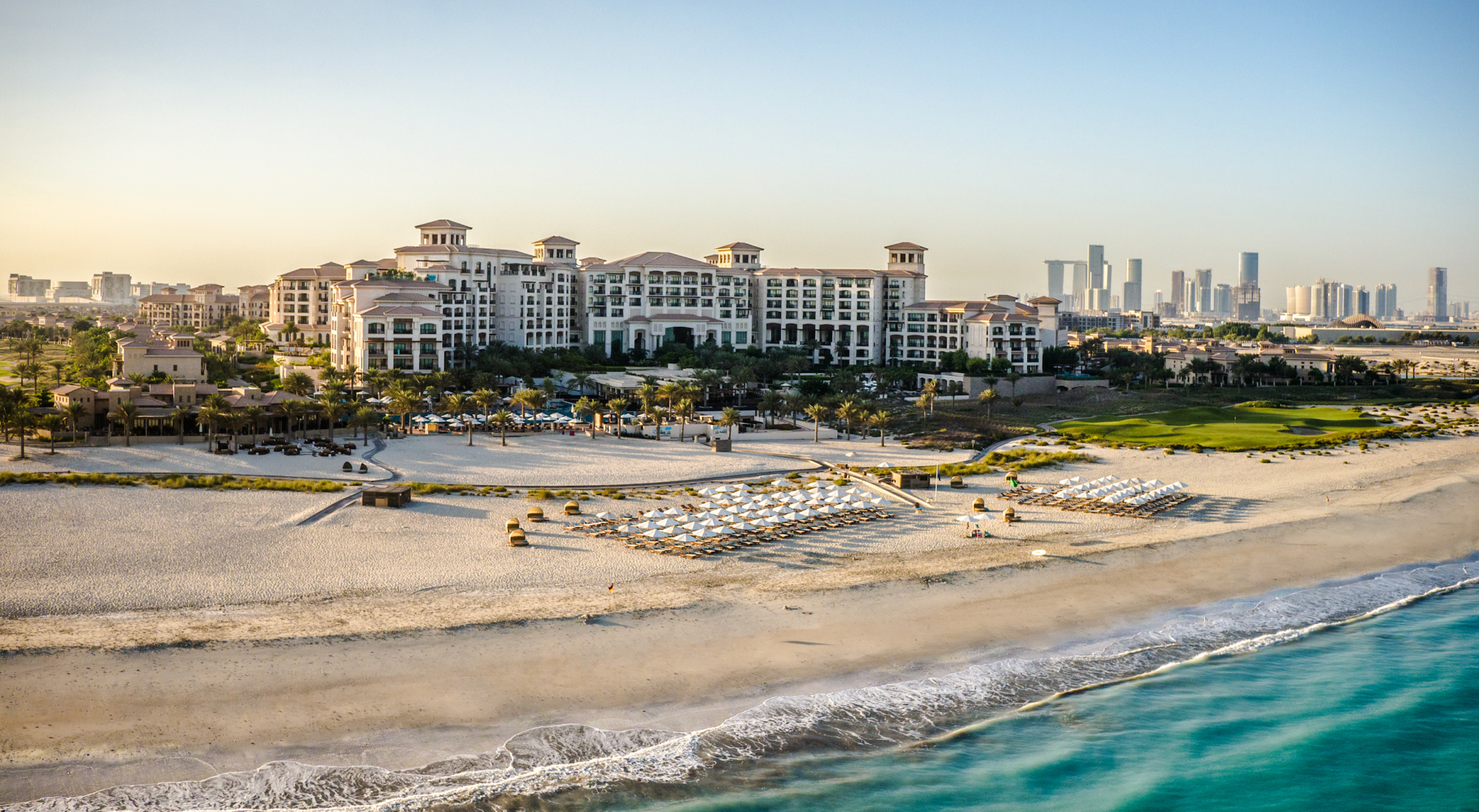 A grand building on a beach in front of the sea.