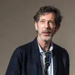 A man in a suit speaking into a microphone.