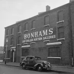 A three-story brick building is seen from an angle. Its facade reads, 