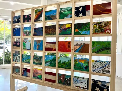 View of postcard-size works on a wood structure that frames them into a grid. 