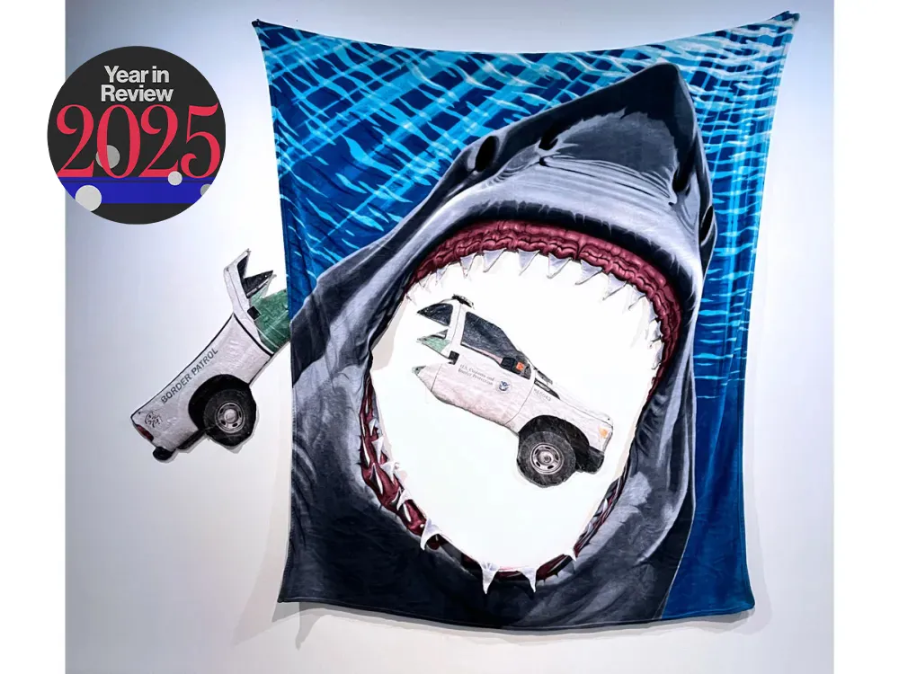 A fleece blanket of the shark from Jaws with its mouth open and that part cut out. In the center and to the left if a chomped-up Border Patrol truck.