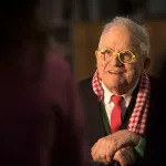 Smiling old man who is seated.