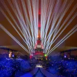 The Eiffel Tower with red with white laser-like lights streaming out from behind it.