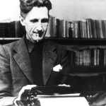 An archival photograph of George Orwell at a typewriter.