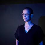 A portrait of a Black woman in a gradient of blue light.