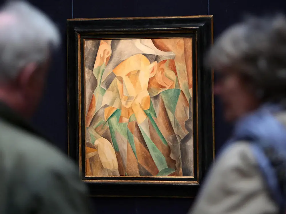 Two people looking at a painting of an abstracted harlequin.