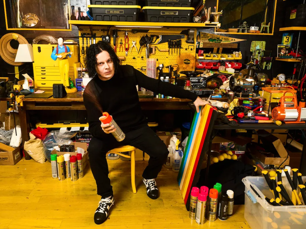 A man in a studio spraypainting a board.