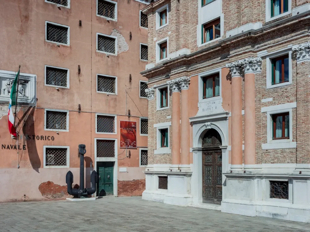 An aged, pale red brick building facade lined with columns.