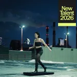 A woman in a black tanktop and tights appears to run in place on a snowy city roof.