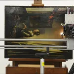 A robotic device scans a Vermeer painting placed on an easel and turned on its side.