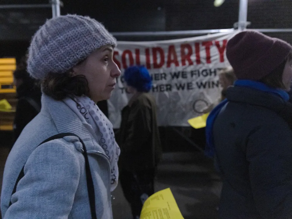 Protesters walk a picket line near a large sign reading Solidarity