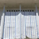 A white tarp with blue stripes hangs on scaffolding outside The Kennedy Center in Washington DC, leaving only part of the name visible