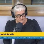 A woman with short grey hair talks into a microphone, wearing headphones. A chryon reads