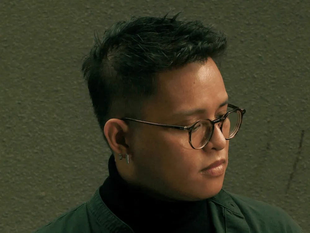 A close-up portrait of a young man in dark glasses.