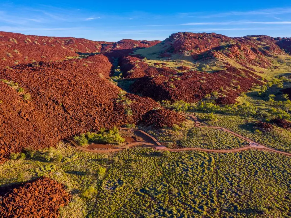 A red mountain range with trees at the foot of its peaks.