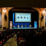 Four panelists on a stage in a beautiful theater.