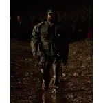 A Black man wearing a large flak jacket, leather pants, and boots in a muddy runway show.