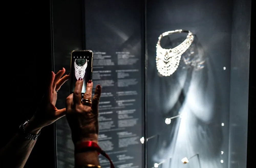 A visitor takes a picture of a necklace made of platinum and diamonds, which dates from 1939, and belonged to the Queen Nazli of Egypt, during the exhibition "Pierres Precieuses" (Gems) on September 15, 2020, at the Grande Galerie de l