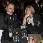 A man and a woman seated a table with glasses on it.