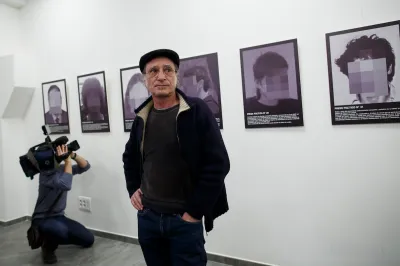 A man standing in front of a row of pictures of pixelated faces.