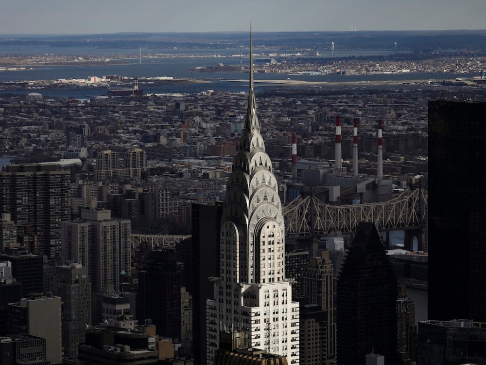 A shiny silver building in an Art Deco style rising above a city skyline.
