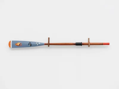 A sculpture of an oar with the trip painted with shells.