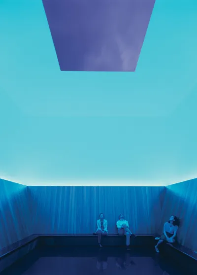People look at the blue sky in a building with a skylight that is cast in cyan blue. 