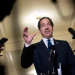 Rep. Jamie Raskin (D-MD) speaks to reporters, wearing a business suit, surrounded by microphones, gesturing with his hand as he speaks.