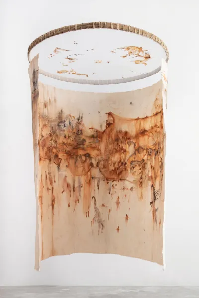 A canvas that is painted with abstract ochre-red marks hangs in a semi-circle from a circle frame.