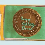 A picture of a cake with chocolate icing and sprinkles says HAPPY BIRTHDAY OMAR. It