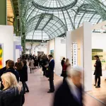 People moving a series of booths lined with paintings.