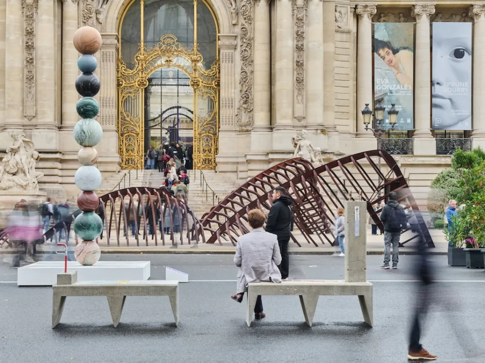 People walking in front of a sculpture composed of a series of stacked orbs.